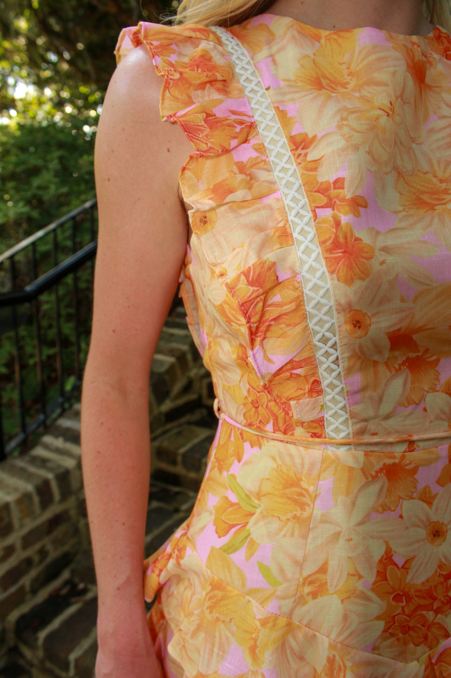 Floral patterned dress in orange and pink with ruffled sleeves and lace trim, perfect for summer occasions.