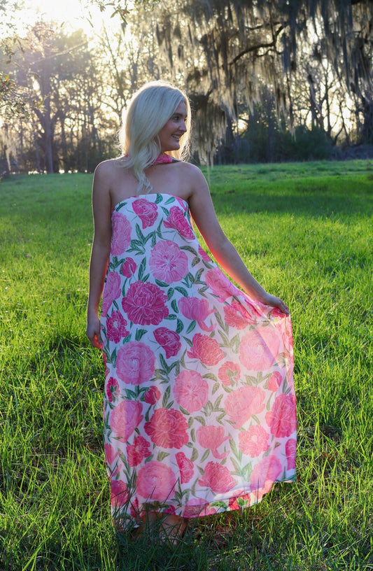 Woman in a pink floral dress standing in a grassy field