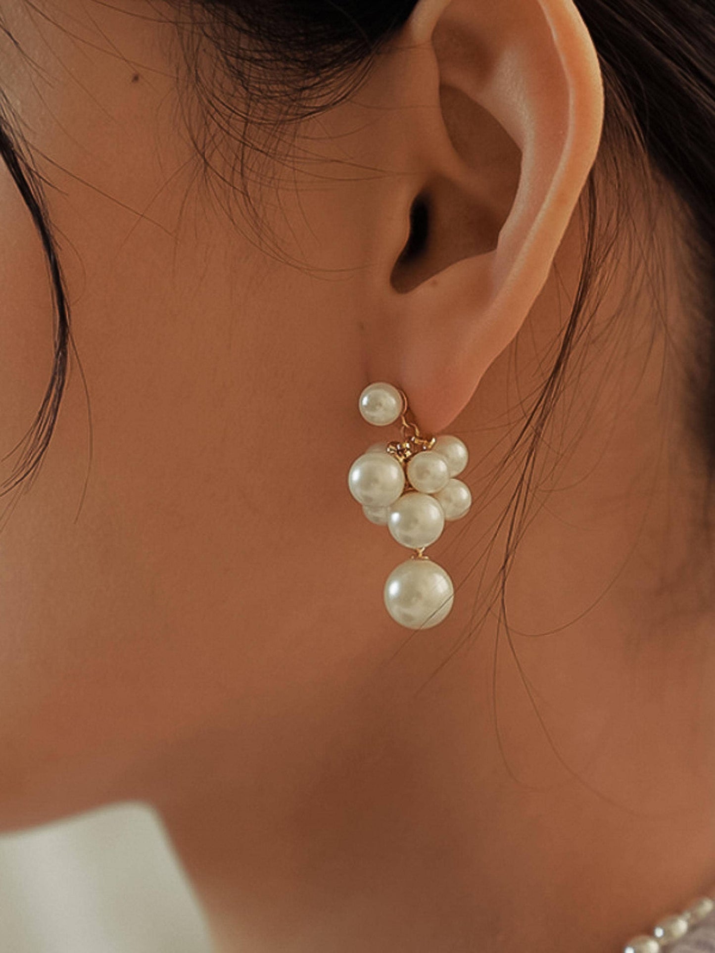 Elegant pearl earrings with a gold finish, featuring multiple round pearls in a clustered design.