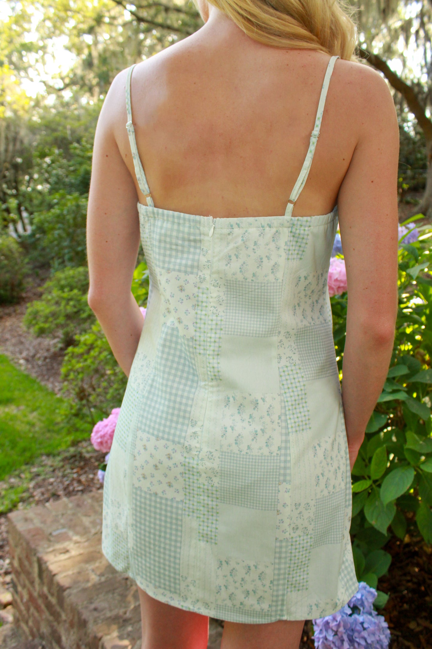 Light green patchwork mini dress with floral and gingham patterns, adjustable straps, perfect for summer.