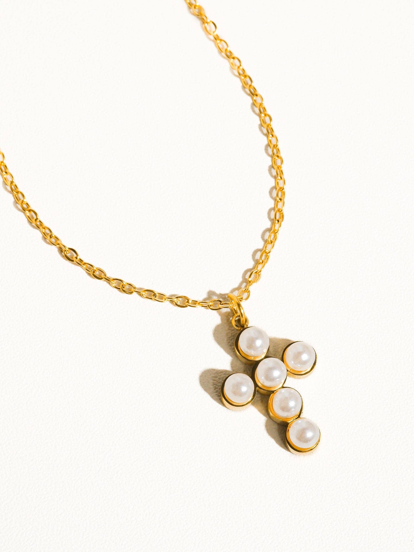 Gold chain necklace with pearl cross pendant, elegant and stylish accessory for everyday wear.