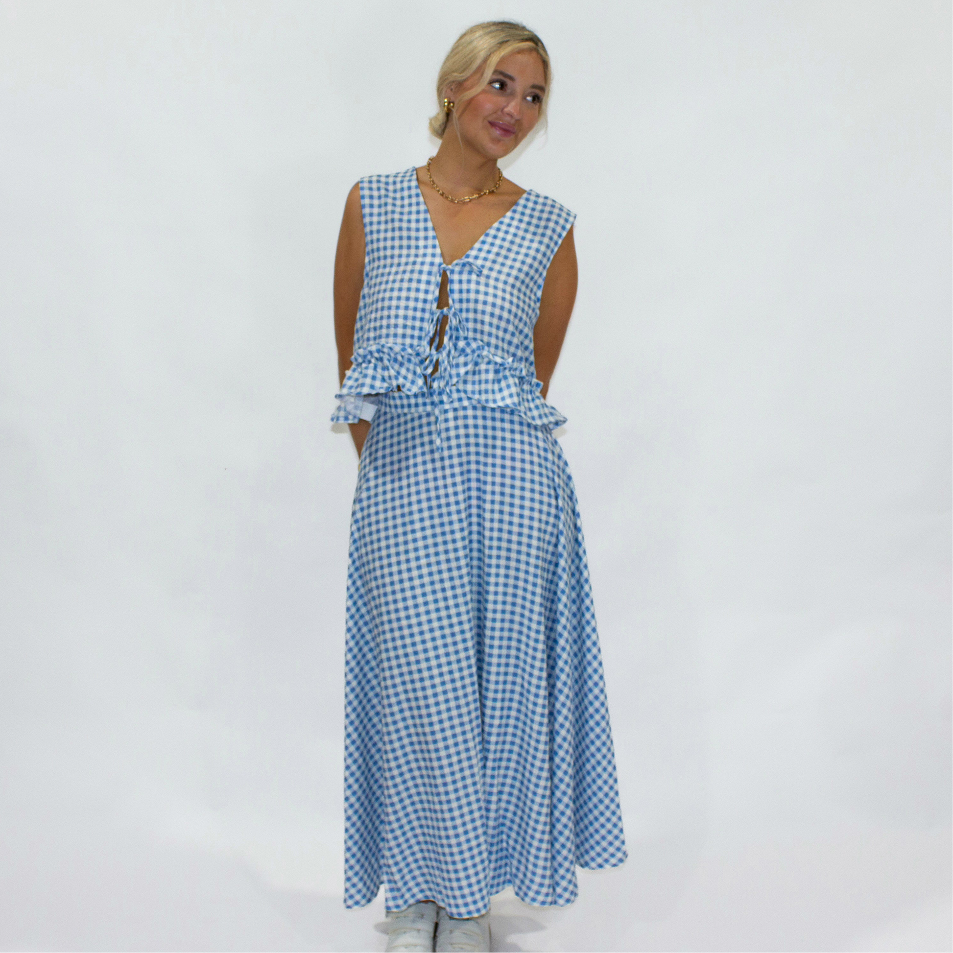Woman wearing a blue gingham dress against a white background