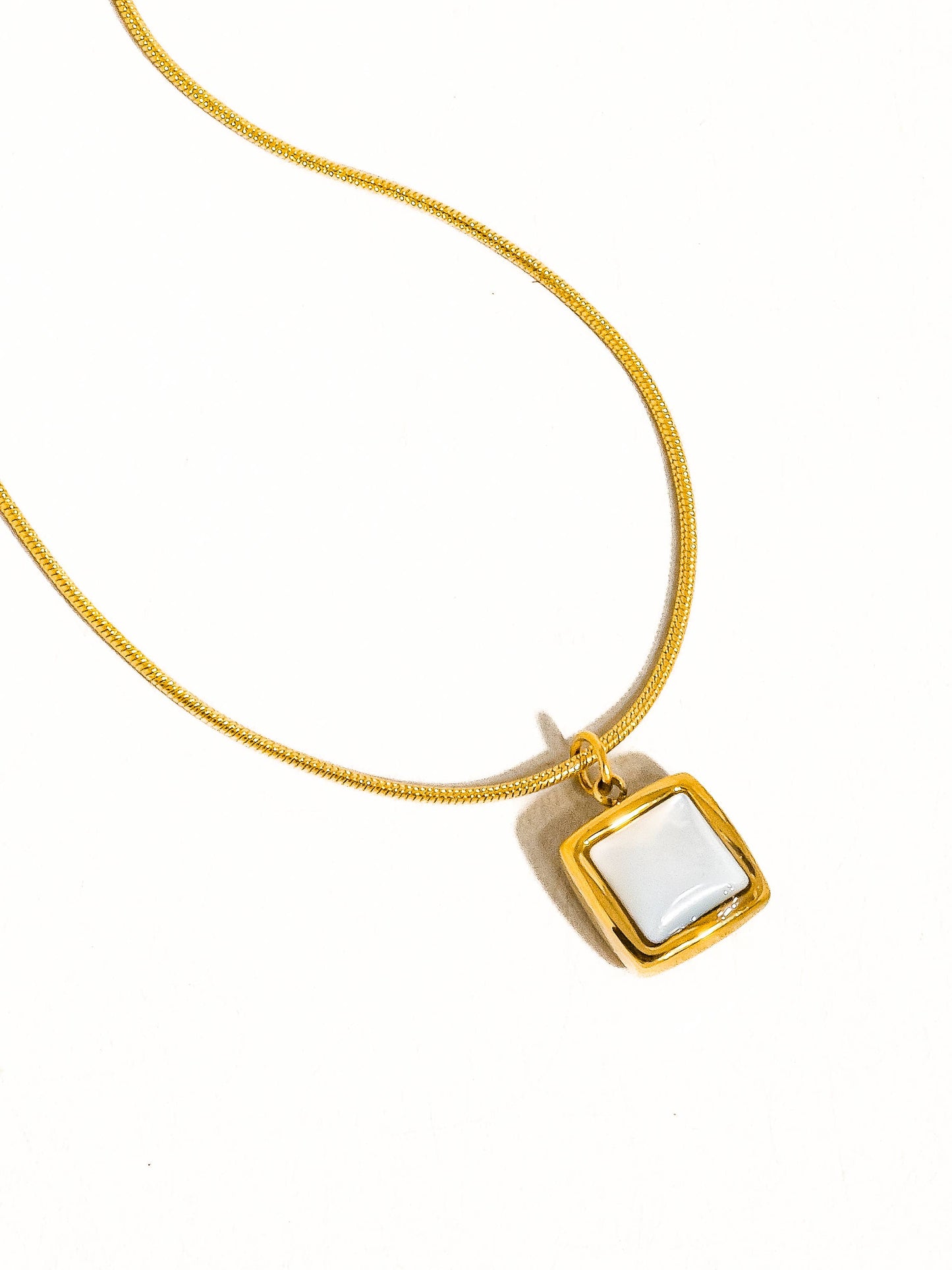 Gold necklace with a square white pendant, perfect for elegant and casual outfits.
