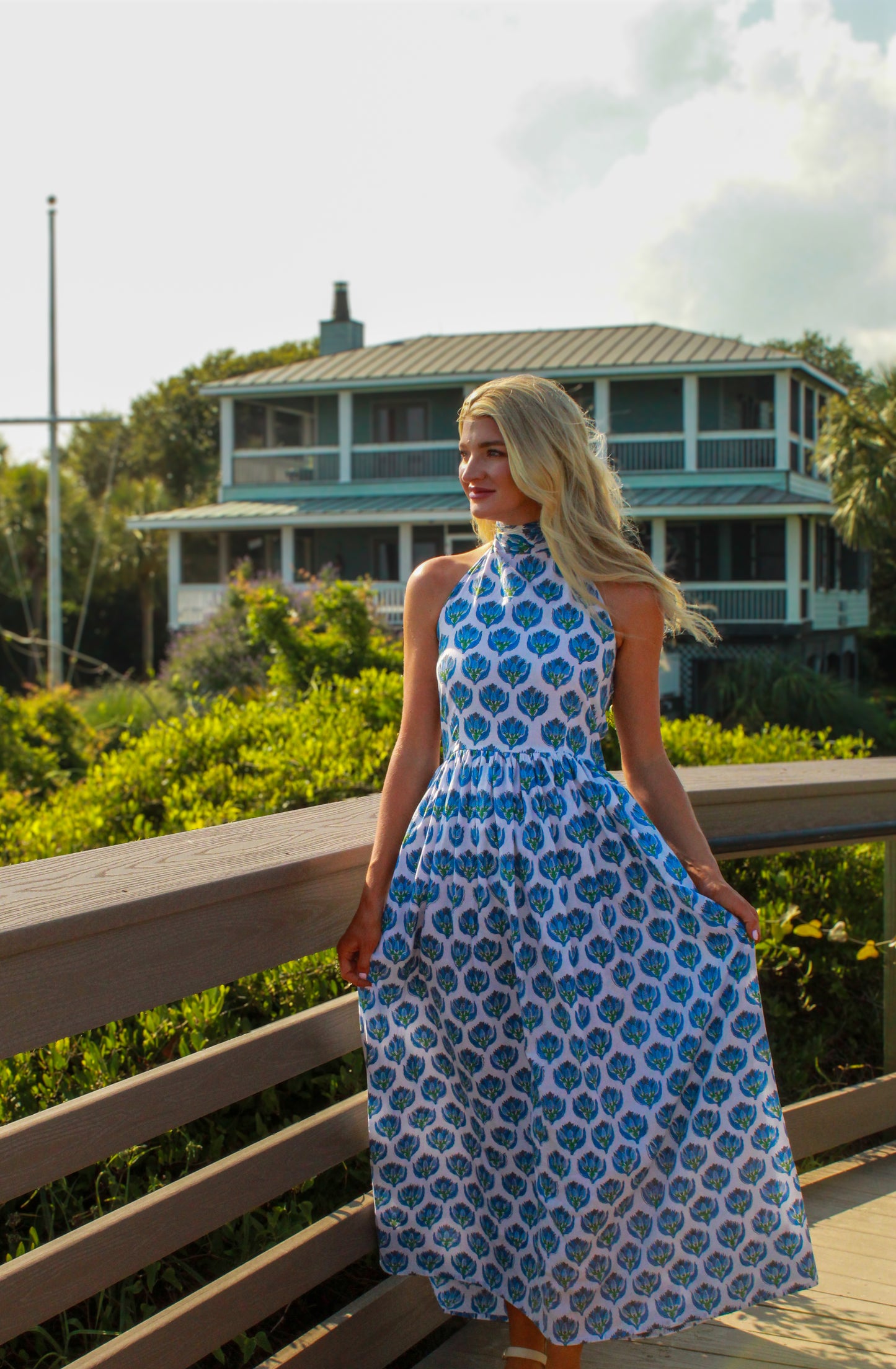 Model wearing a blue and white floral maxi dress with a high neckline and flowing skirt.