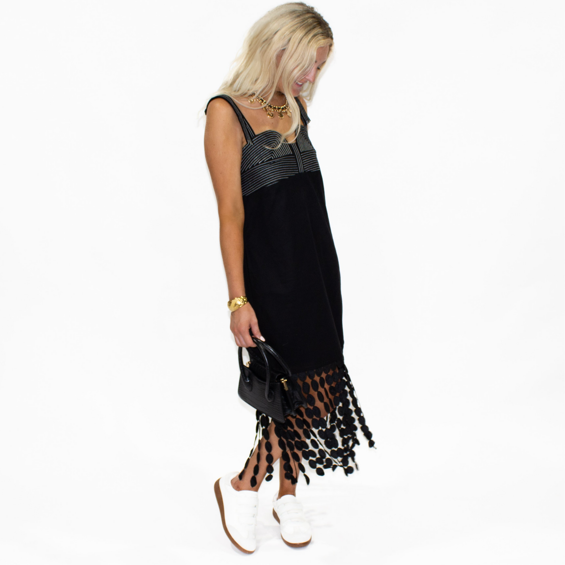 Woman wearing a black dress with a patterned hem on a white background