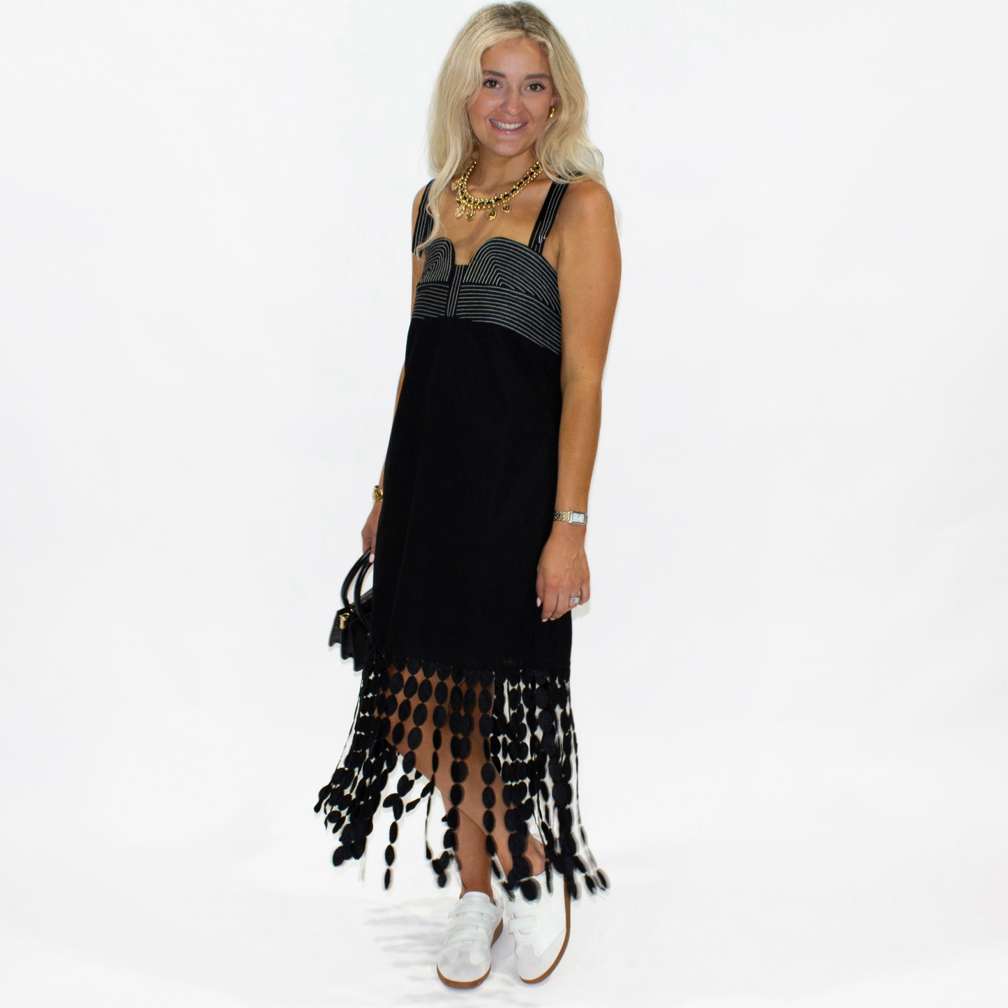 Woman wearing a black dress with fringe details on a white background