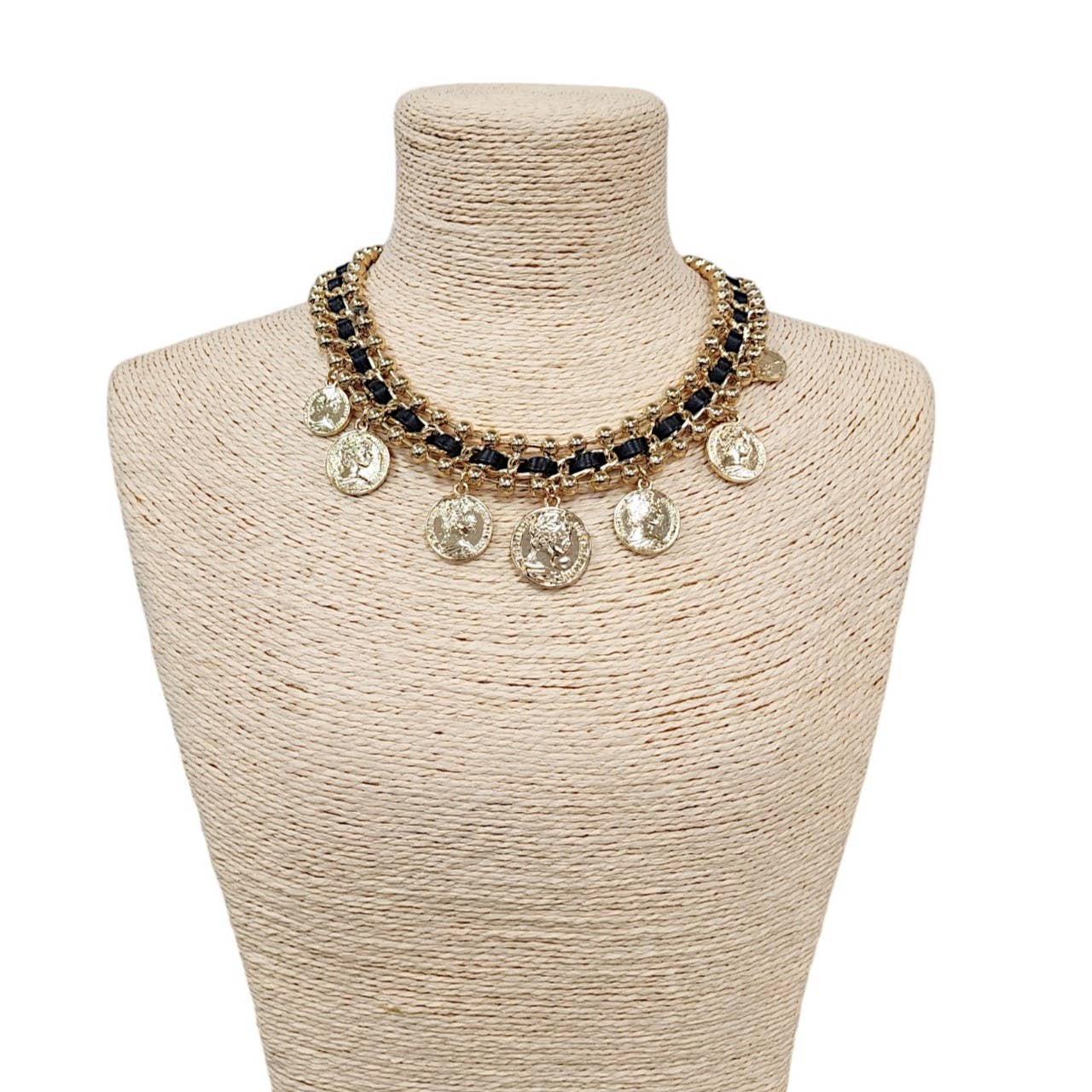 Necklace with coins and beads on a mannequin bust against a white background