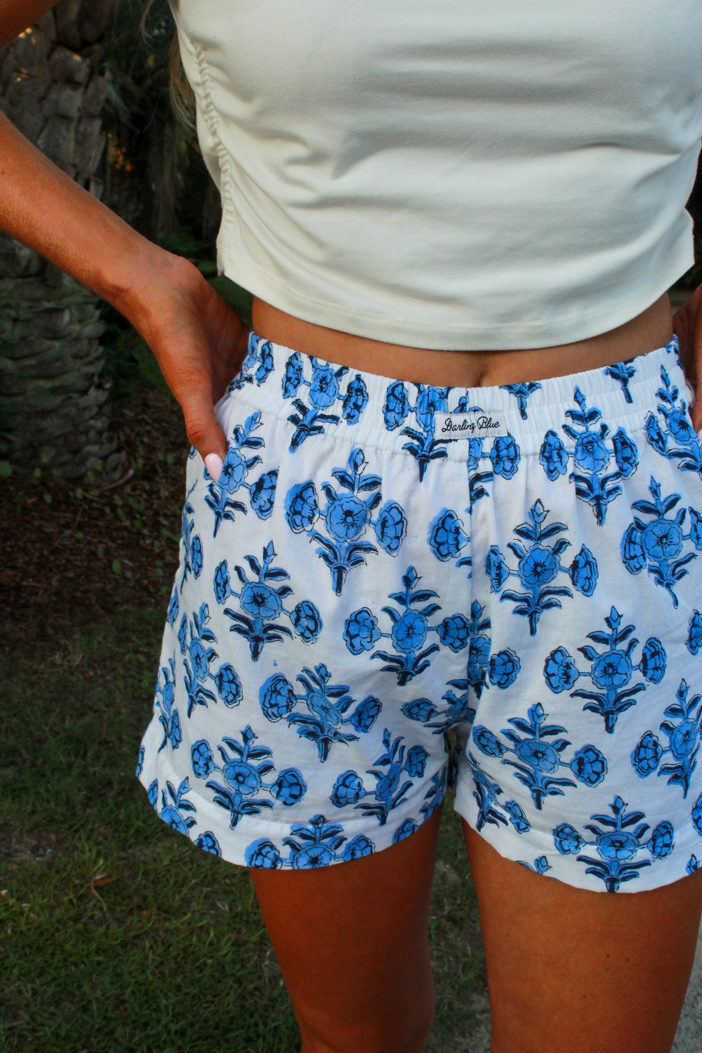 White floral print shorts with blue design, featuring an elastic waistband for comfort.