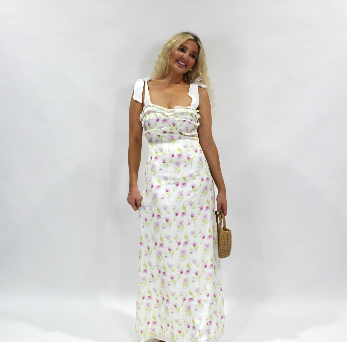 Women's floral maxi dress, white with pink and green print, ruffled neckline, and adjustable straps.