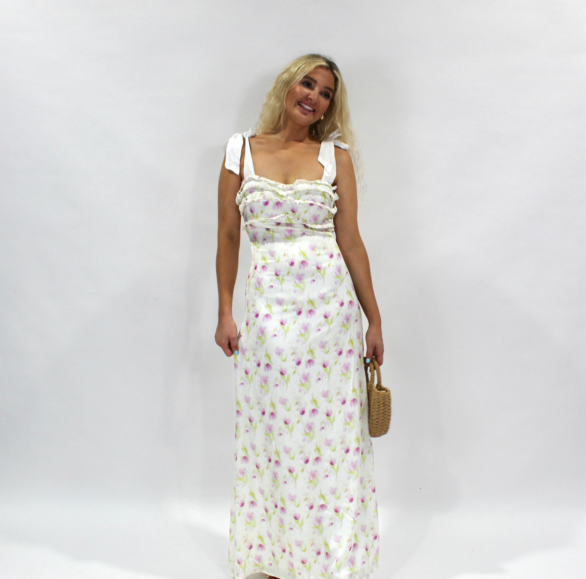 Women's floral maxi dress, white with pink and green print, ruffled neckline, and adjustable straps.