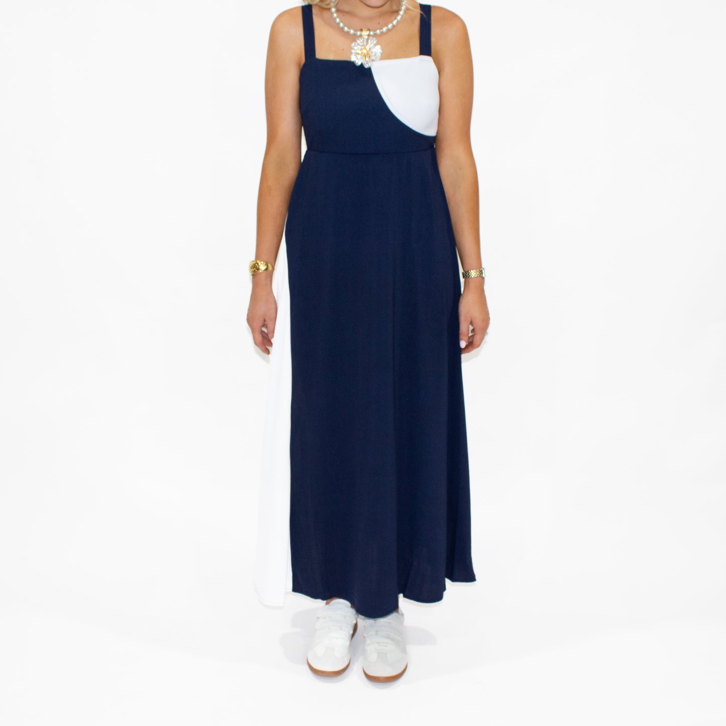 Woman wearing a navy blue dress with a white top on a white background