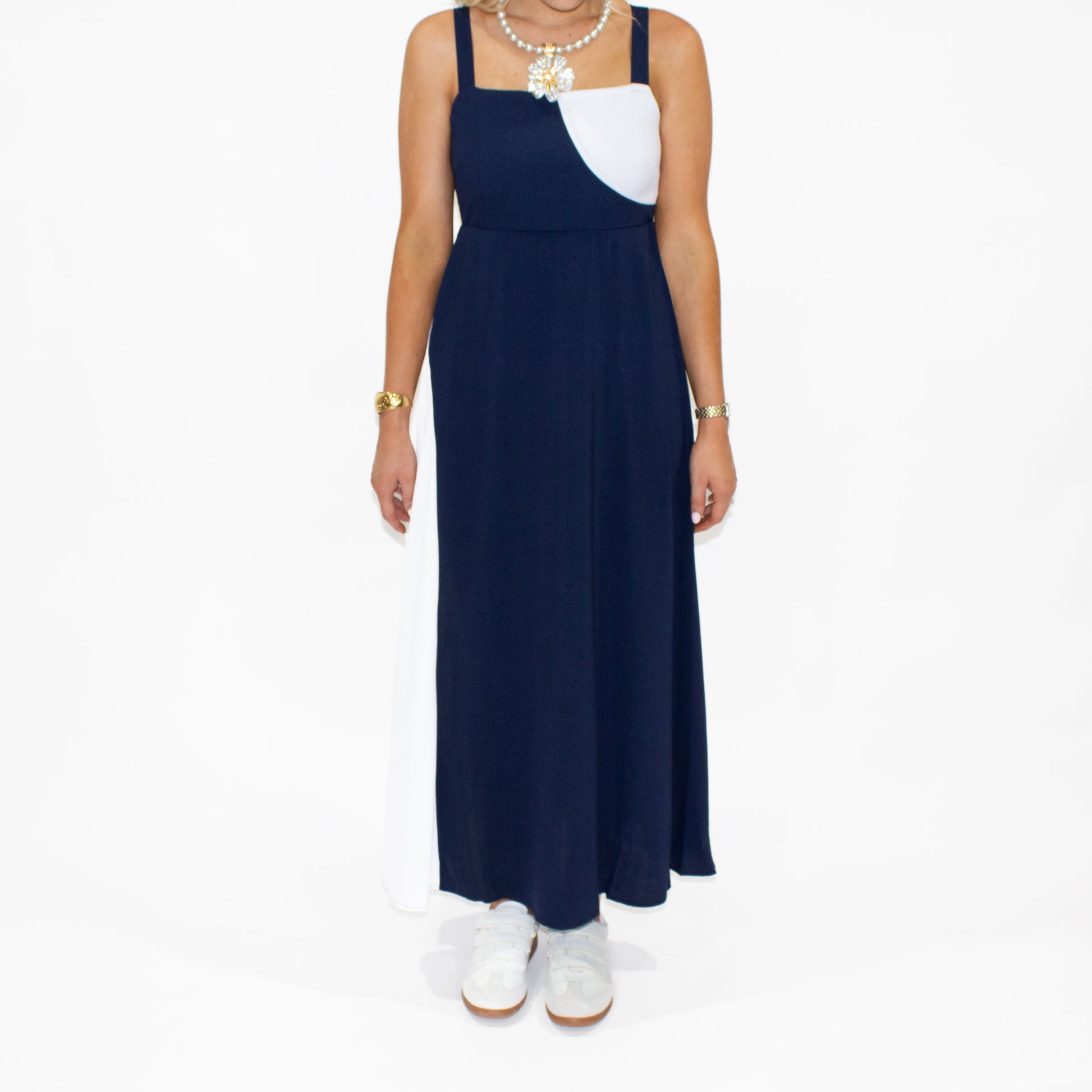Woman wearing a navy blue dress with a white top on a white background