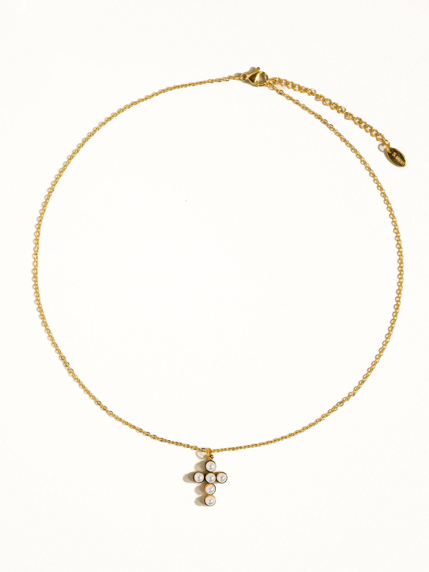 Gold necklace with a unique cross pendant featuring pearls, perfect for elegant styling.