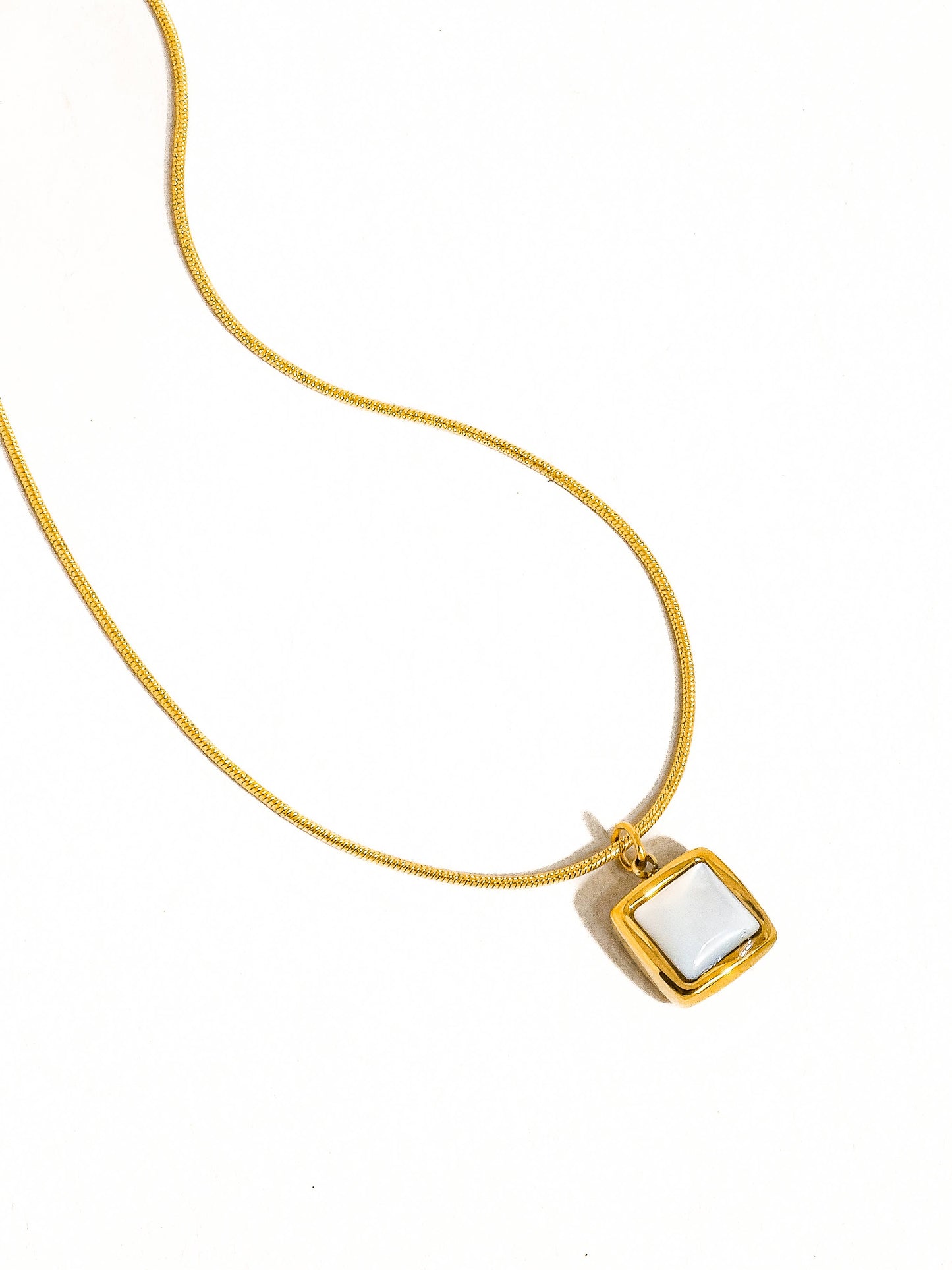 Elegant gold necklace with a square white gemstone pendant, ideal for stylish accessories.