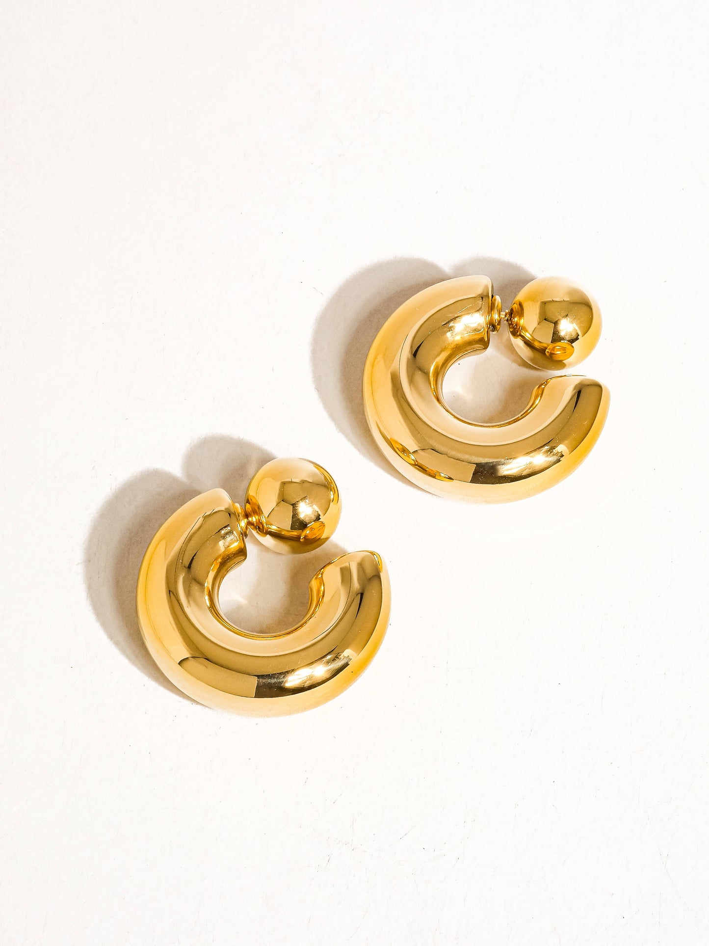 Stylish gold metal hoop earrings with a unique sculptural design for a modern look.