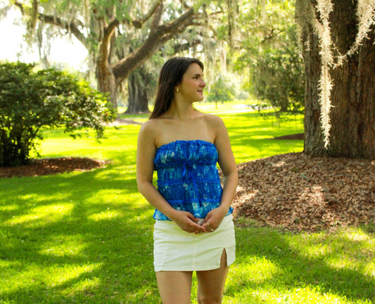 Women's blue strapless top with ruffled design, perfect for summer, paired with a white mini skirt.