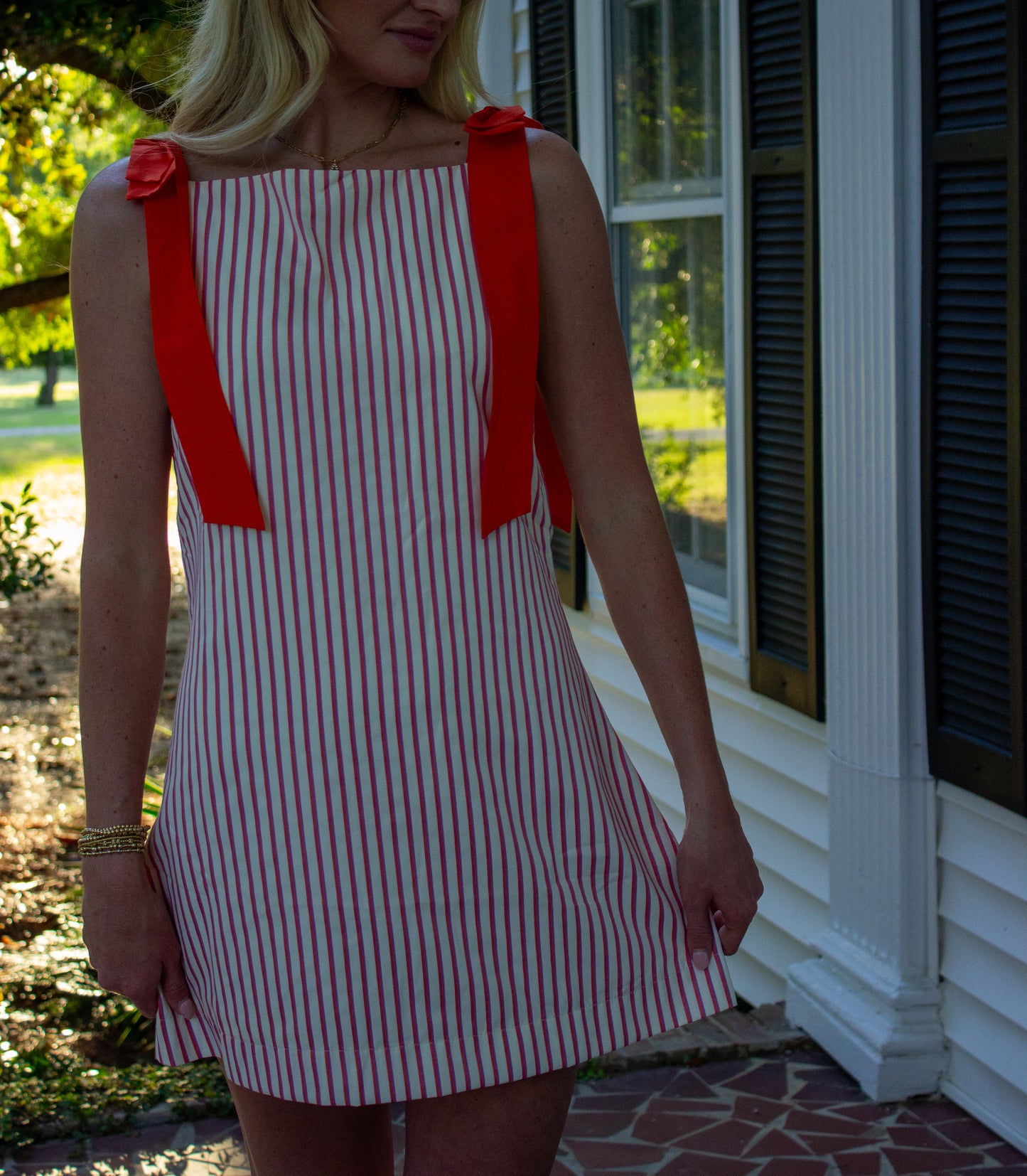 Red and white striped sleeveless dress with bow details on shoulder, perfect for casual summer wear.