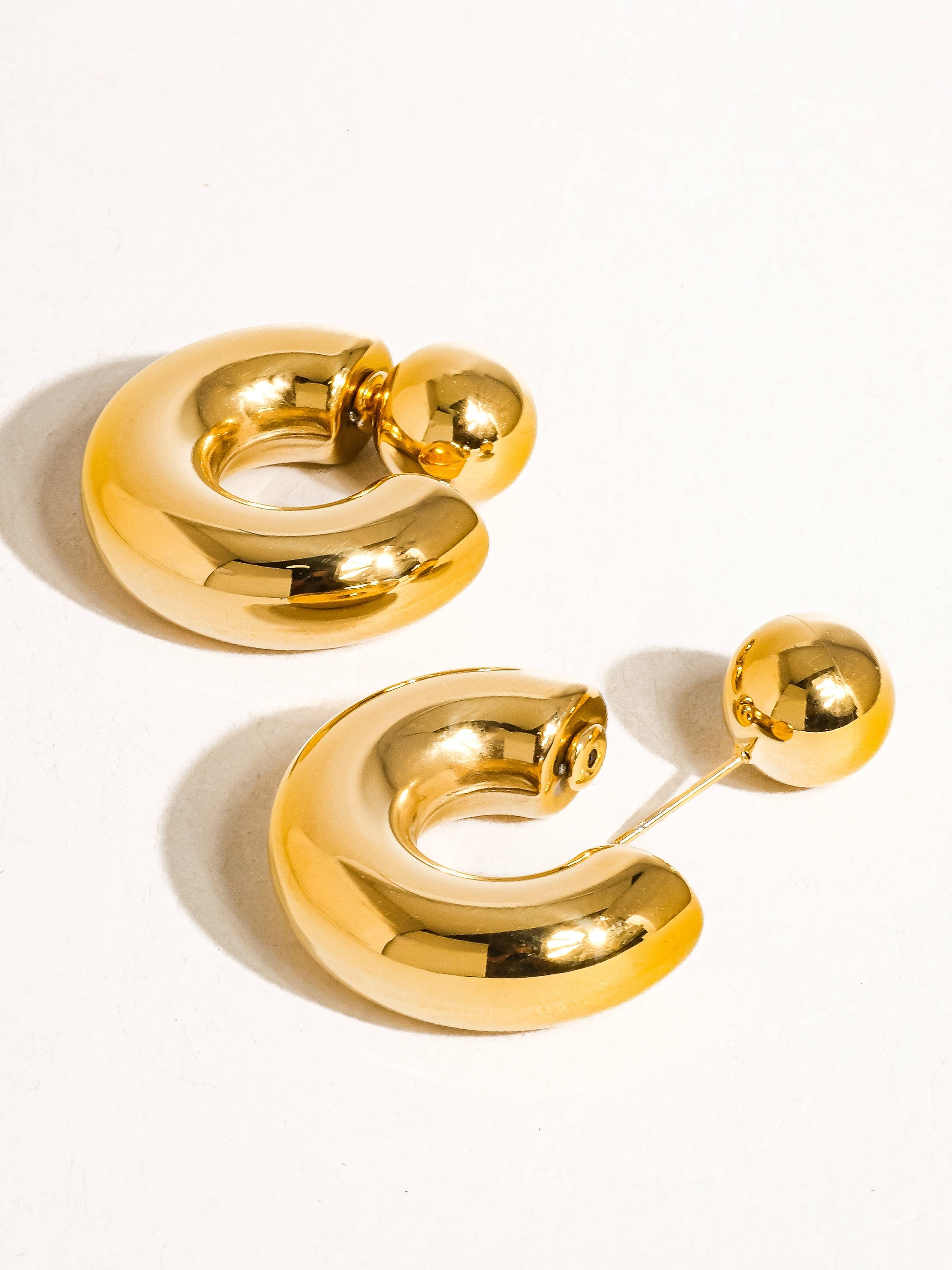 Stylish gold hoop earrings, featuring a unique rounded design and polished finish for a modern look.