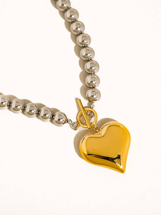 Silver beaded necklace with a gold heart pendant and toggle clasp for a stylish touch.