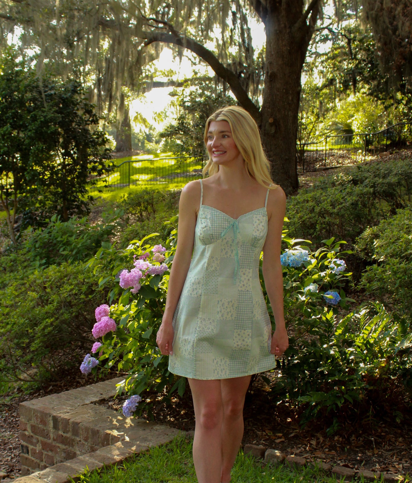 Light green sleeveless dress with lace patterns, perfect for summer outings in a garden setting.