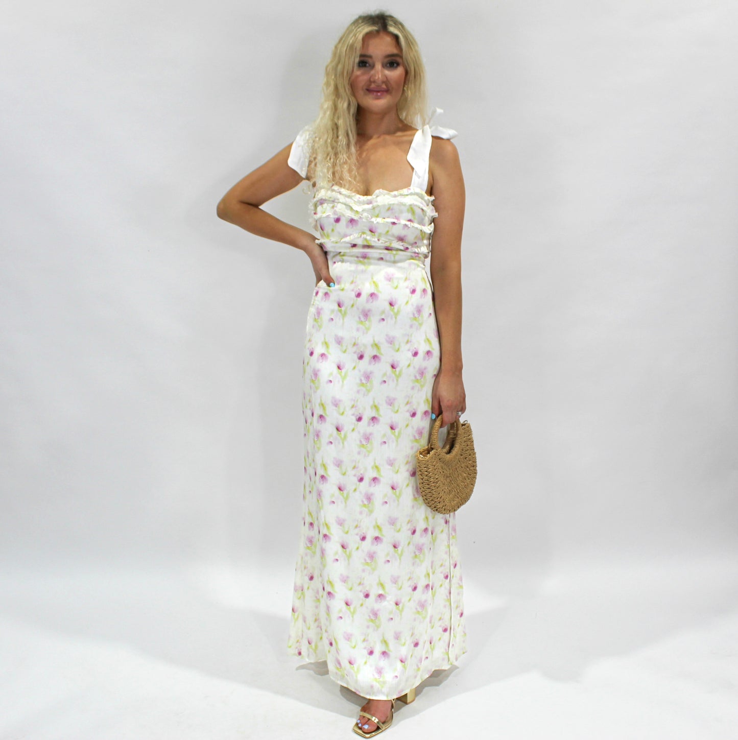 Floral maxi dress in white with pink accents, featuring ruffle details and tie straps, ideal for summer events.