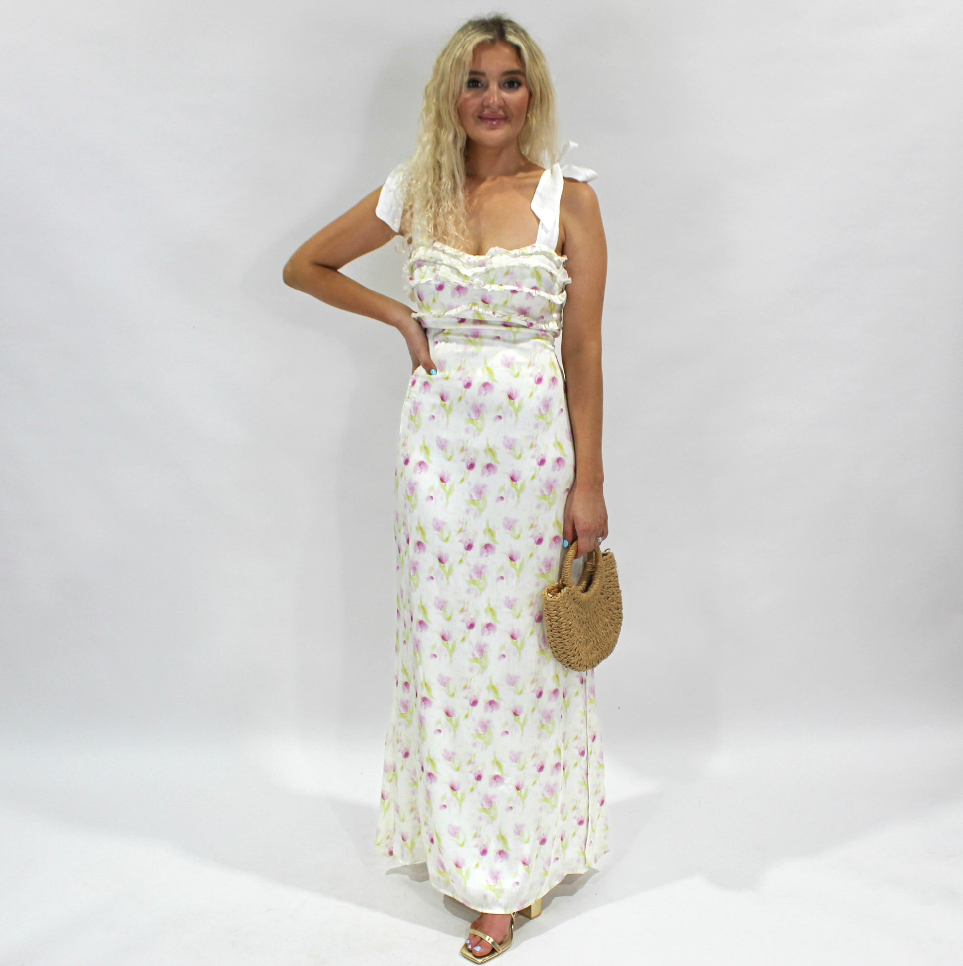 Floral maxi dress in white with pink accents, featuring ruffle details and tie straps, ideal for summer events.