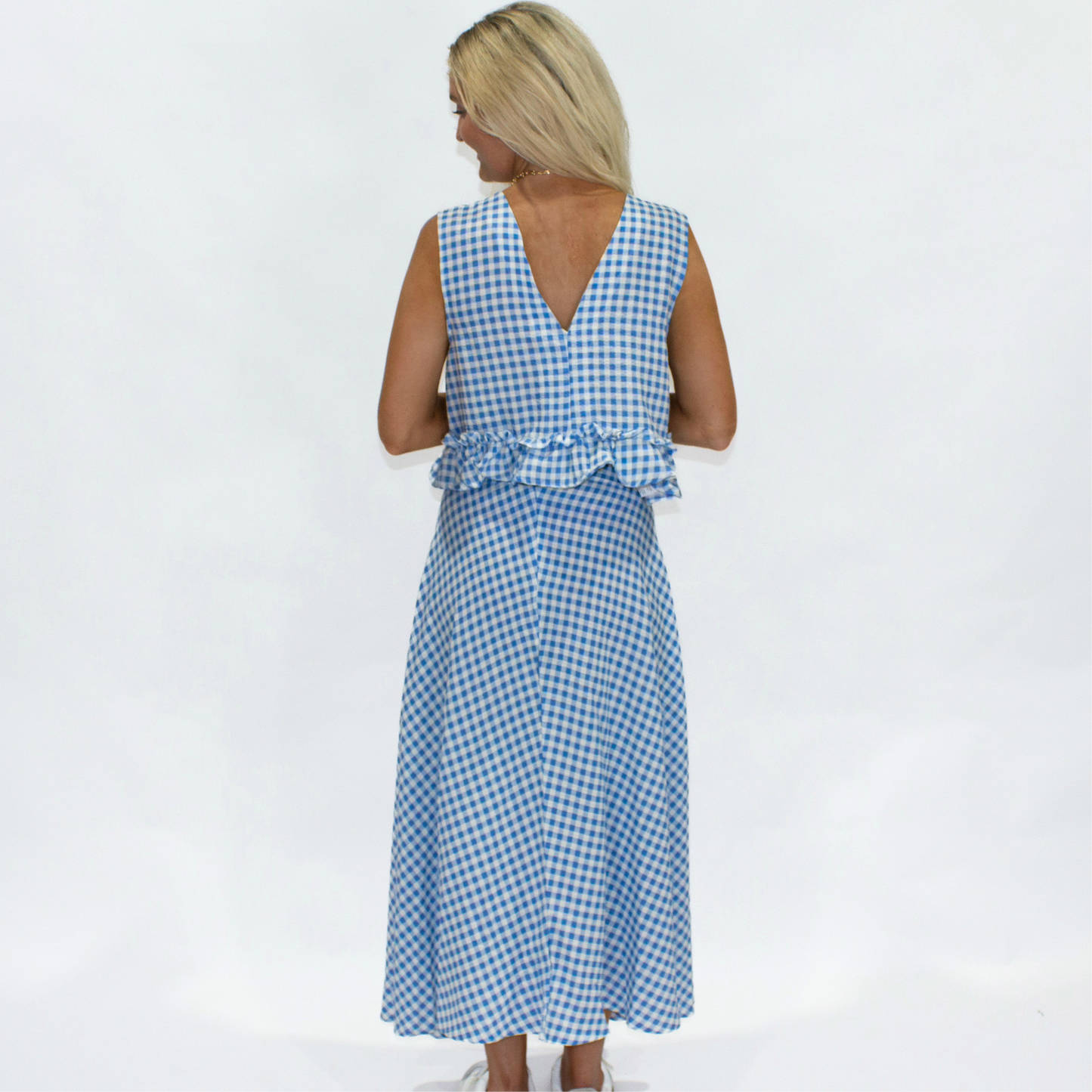 Woman wearing a blue and white checkered dress on a white background