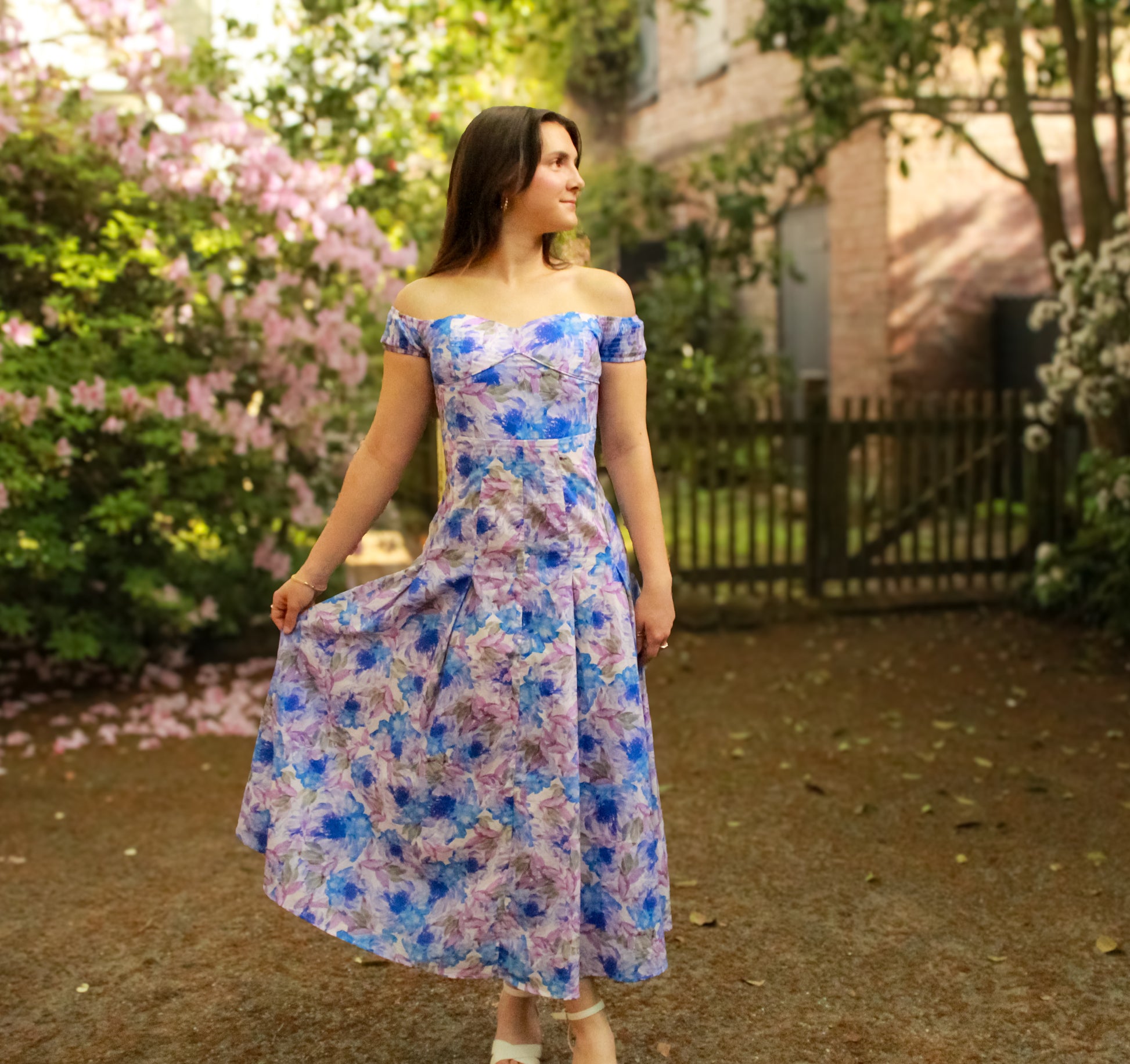 Off-shoulder floral dress in blue and purple, featuring a fitted bodice and flowing skirt, perfect for spring.