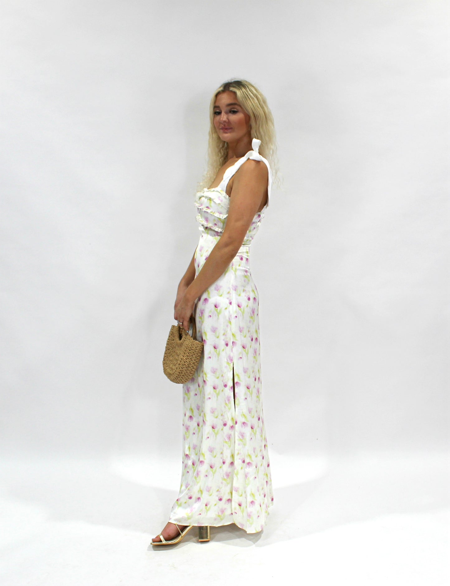 Floral maxi dress in white with purple accents, featuring ruffled detailing and shoulder ties.