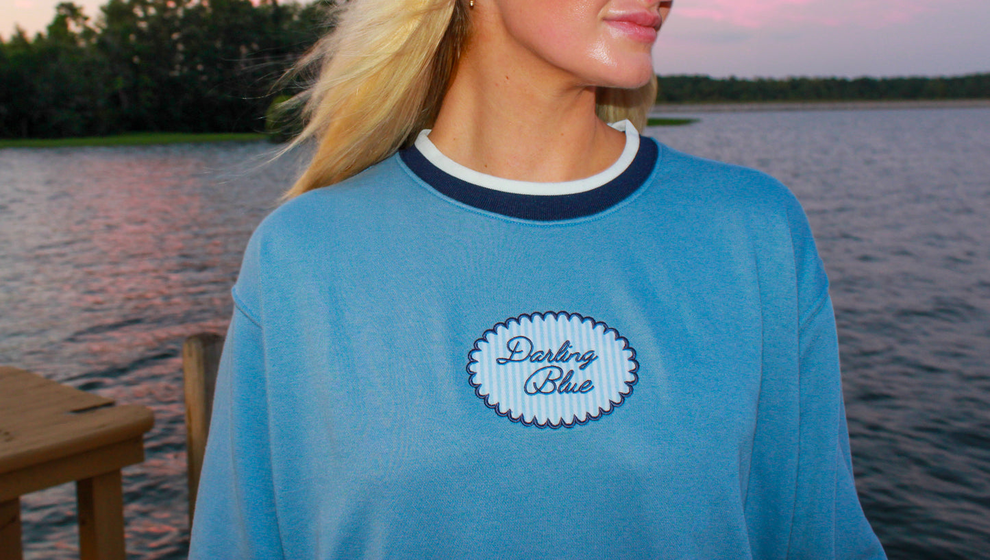 Woman wearing a blue shirt with a logo by a lake