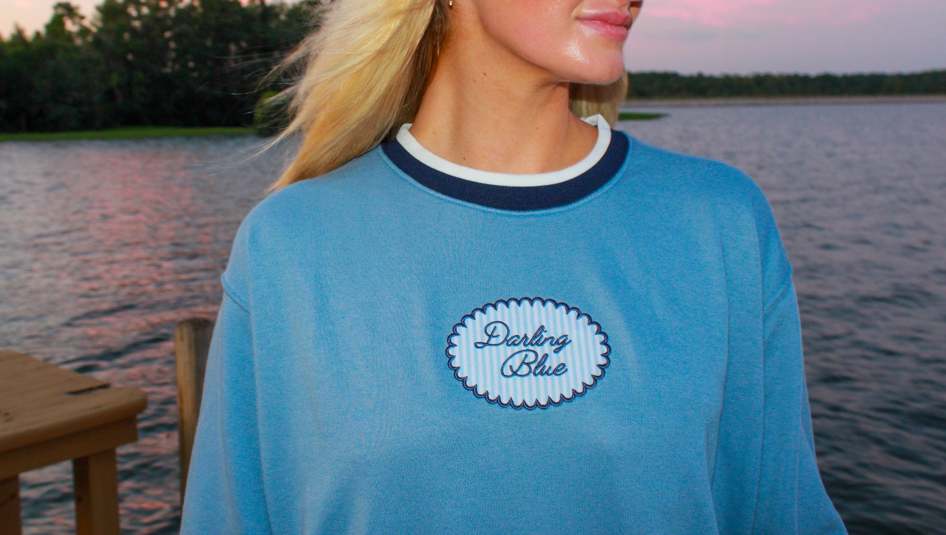 Woman wearing a blue shirt with a logo by a lake