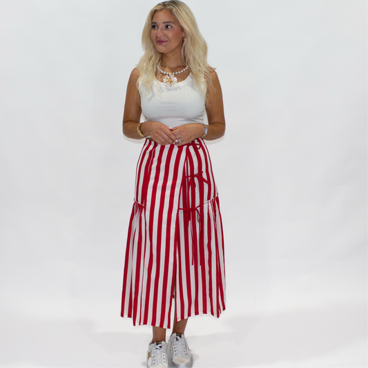 Woman wearing a white top and red and white striped skirt on a white background