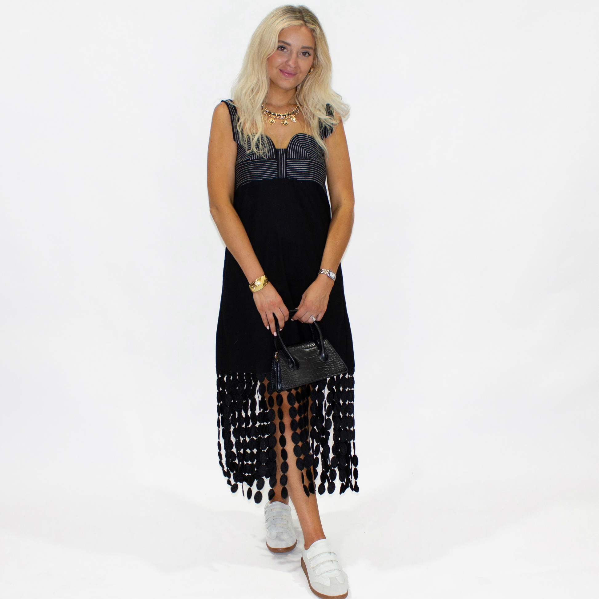 Woman wearing a black dress with fringe details on a white background