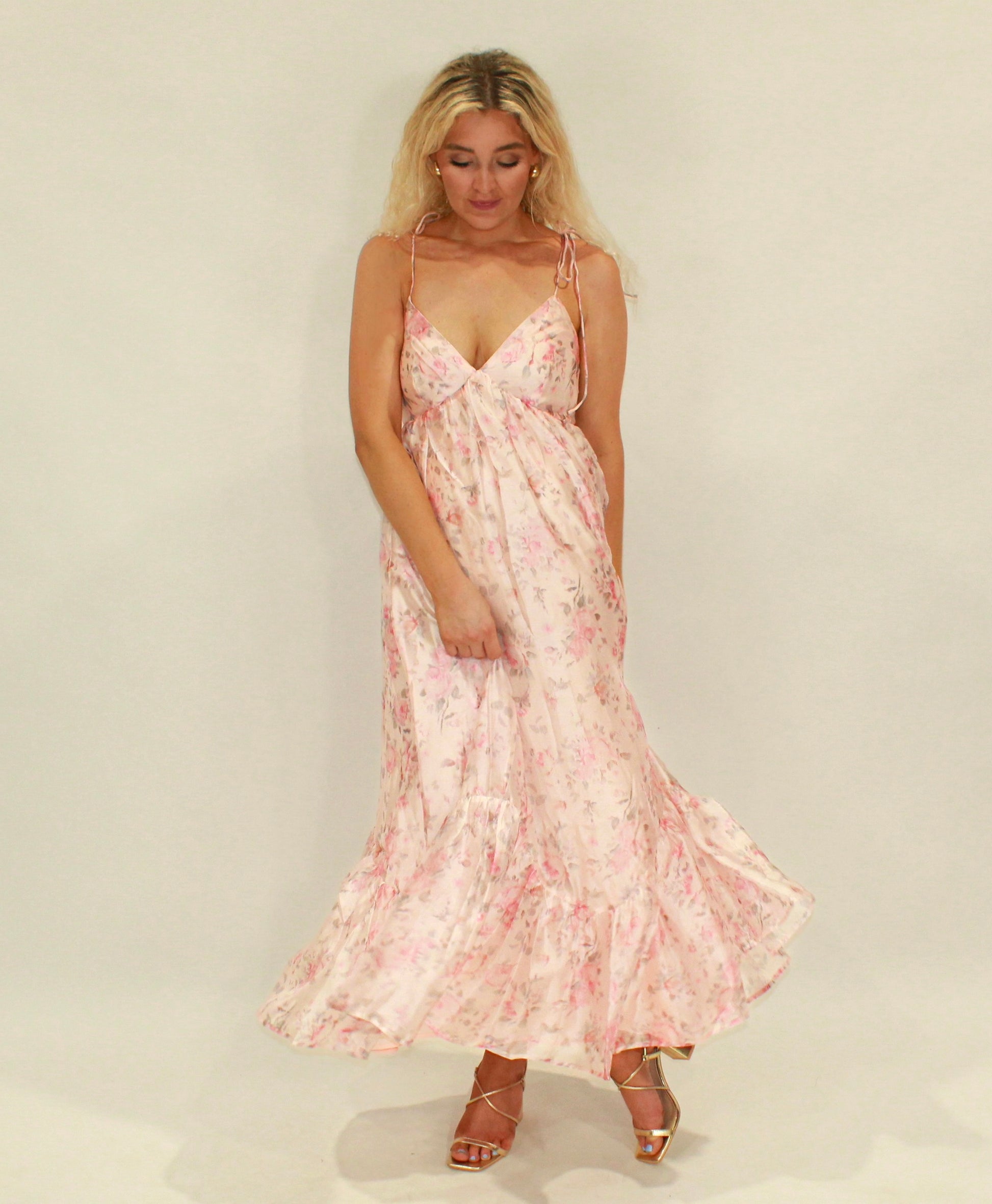 Floral pink maxi dress with spaghetti straps and ruffled hem, perfect for summer occasions.
