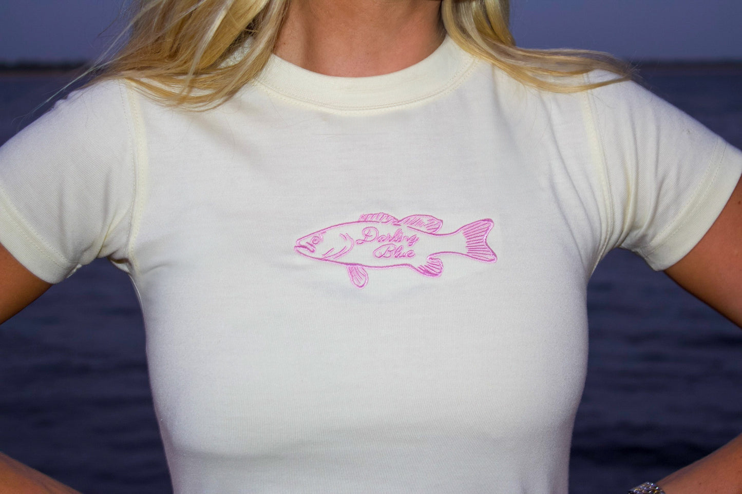 Person wearing a white t-shirt with a pink fish design and text on a blue background