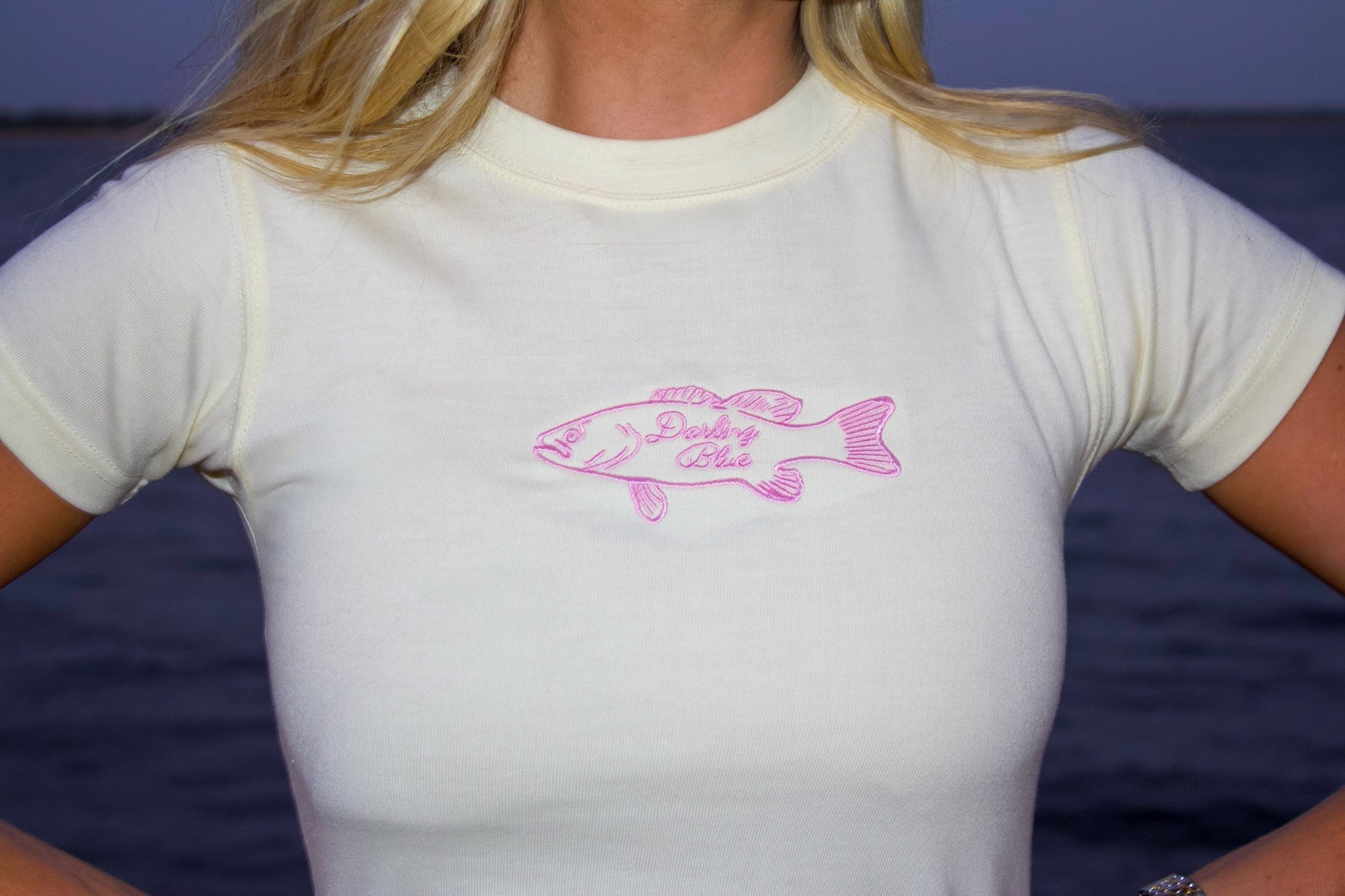 Person wearing a white t-shirt with a pink fish design and text on a blue background