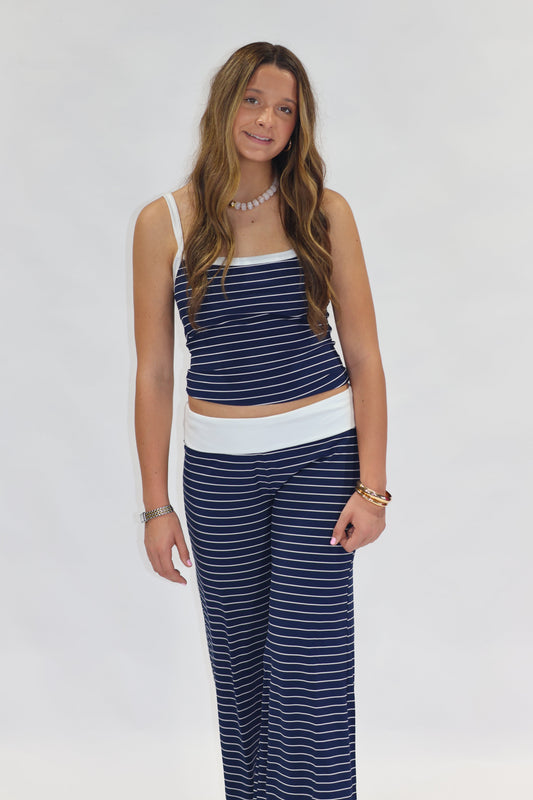A woman modeling a matching two-piece loungewear set consisting of a navy blue and white striped crop top and wide-leg pants, set against a plain white studio background.