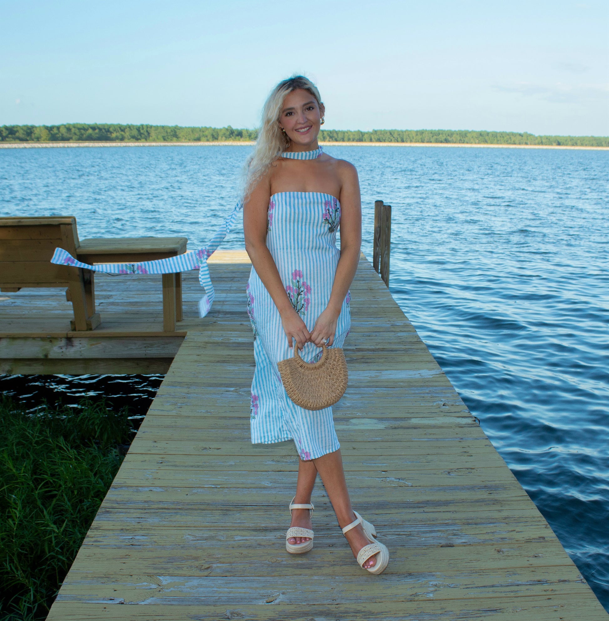 Woman in a striped dress standing on a dock by a lake