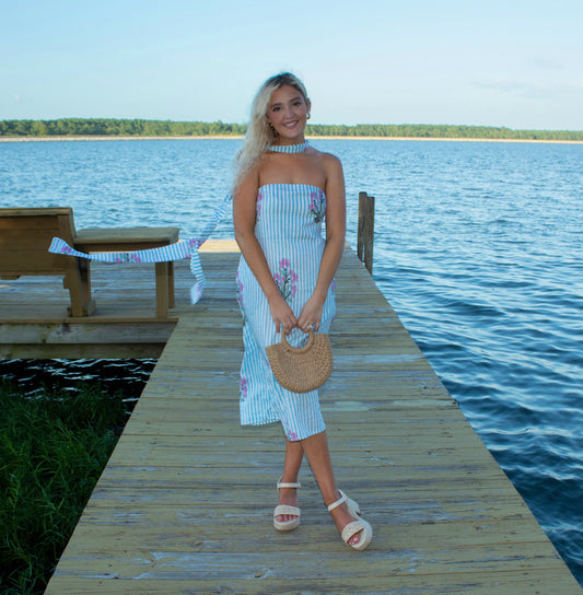 Woman in a striped dress standing on a dock by a lake