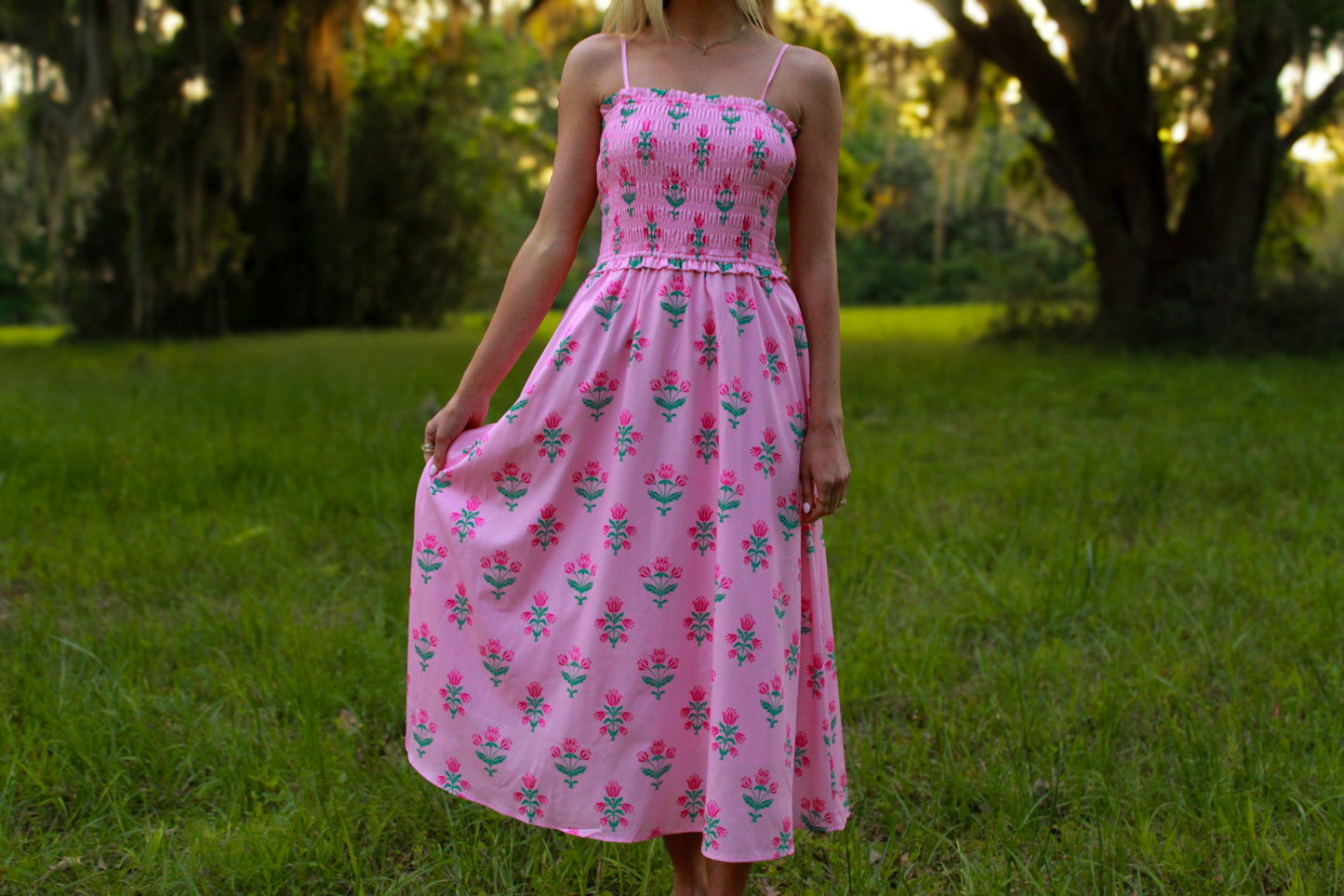 Light pink floral dress with smocked bodice and spaghetti straps, perfect for summer occasions.