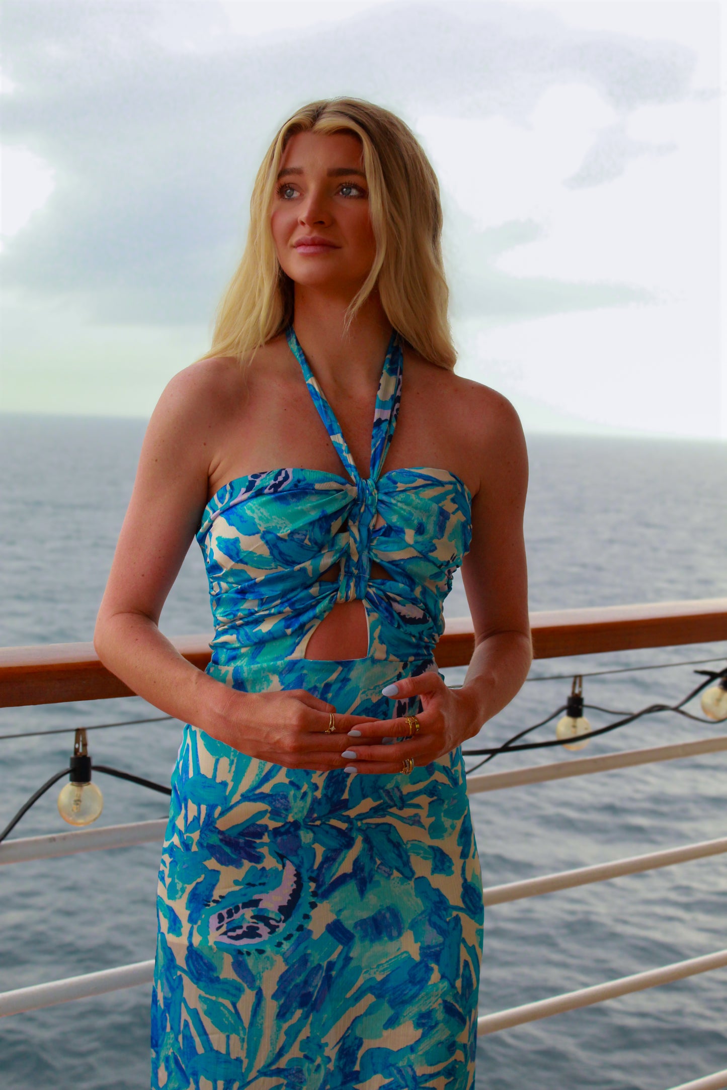 Women’s halter neck dress in vibrant blue floral print, featuring a cutout and ruching detail.