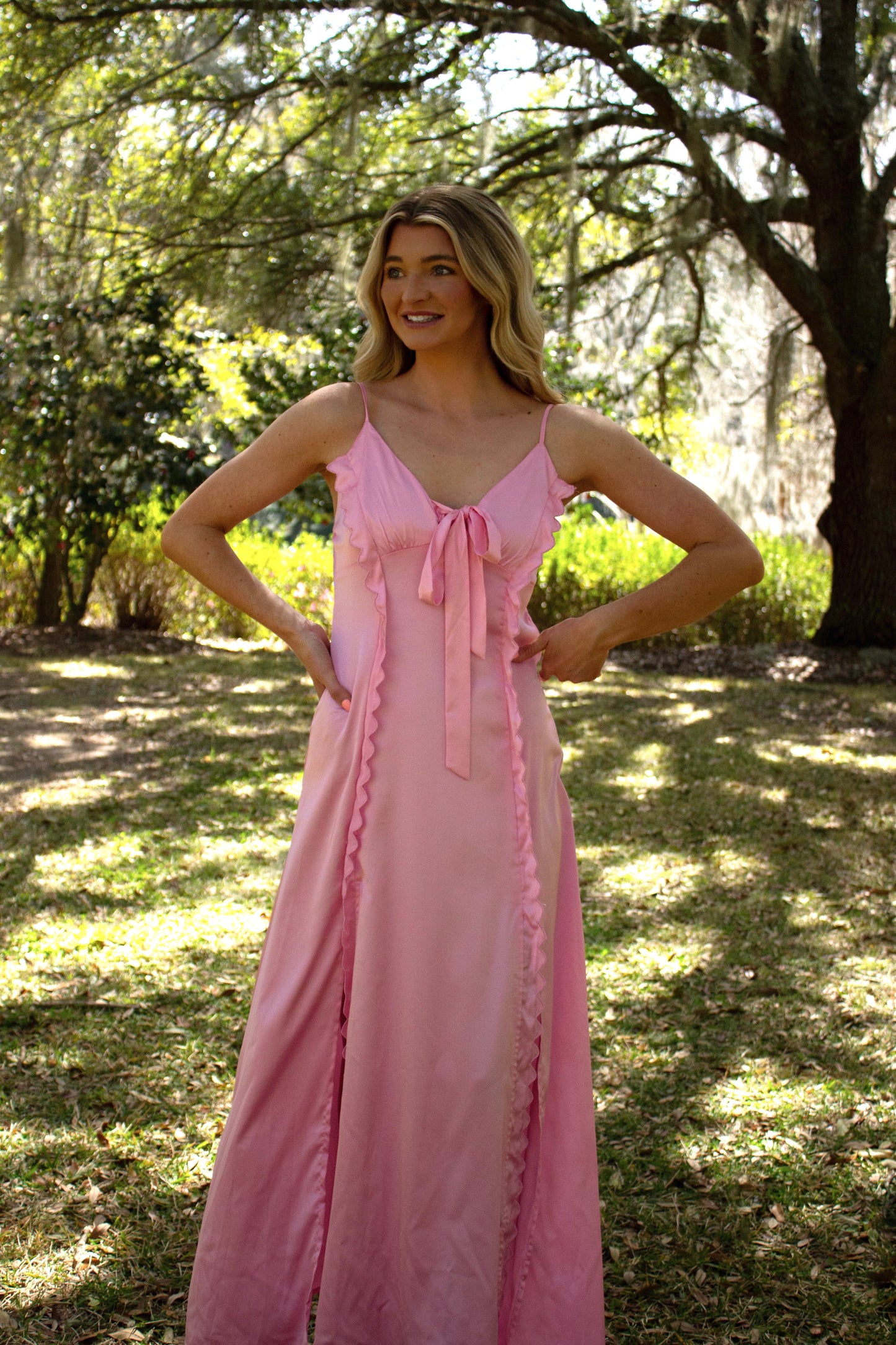 Elegant pink maxi dress with ruffled details and a bow, perfect for summer outings.