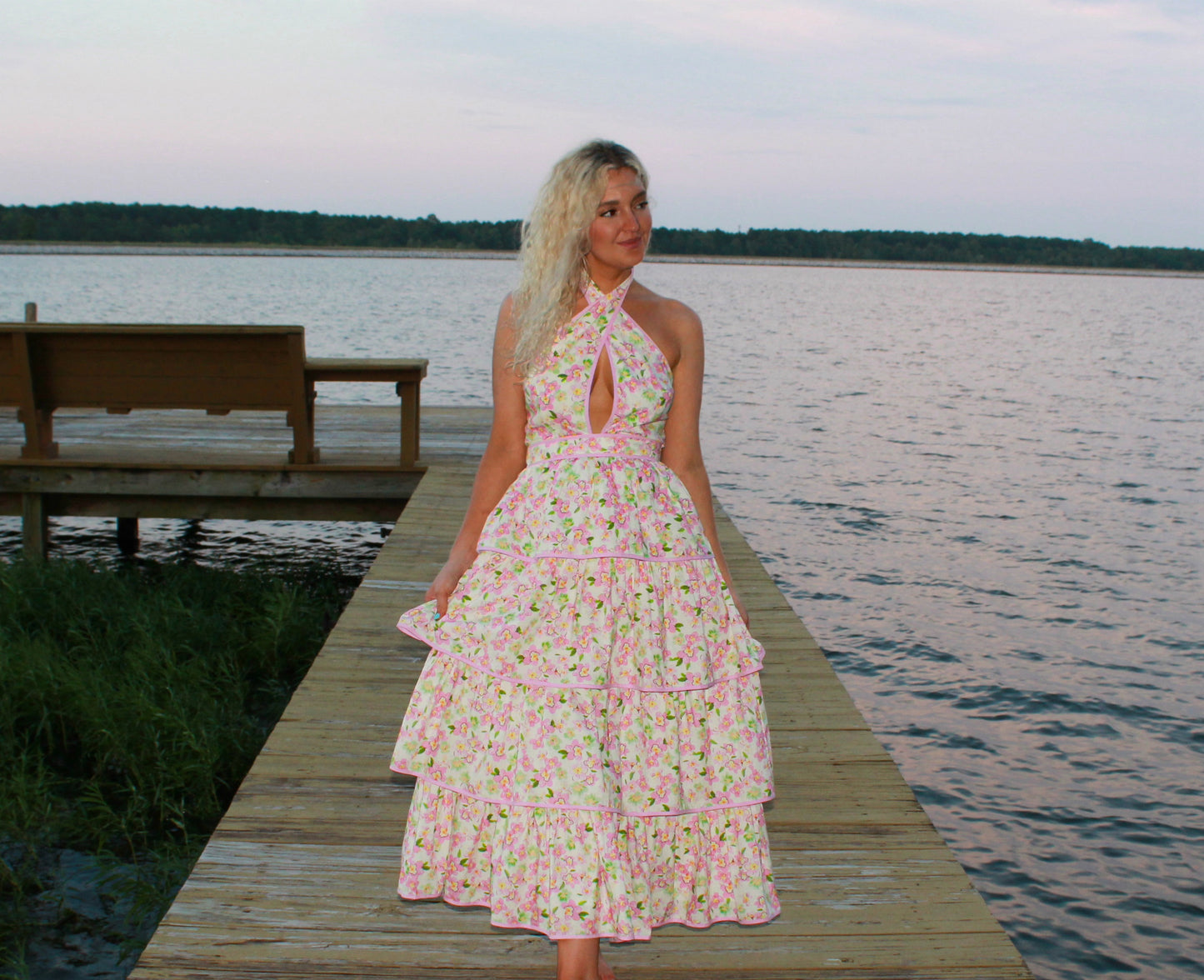 Floral pink halter neck dress with tiered skirt, perfect for summer outings by the water.