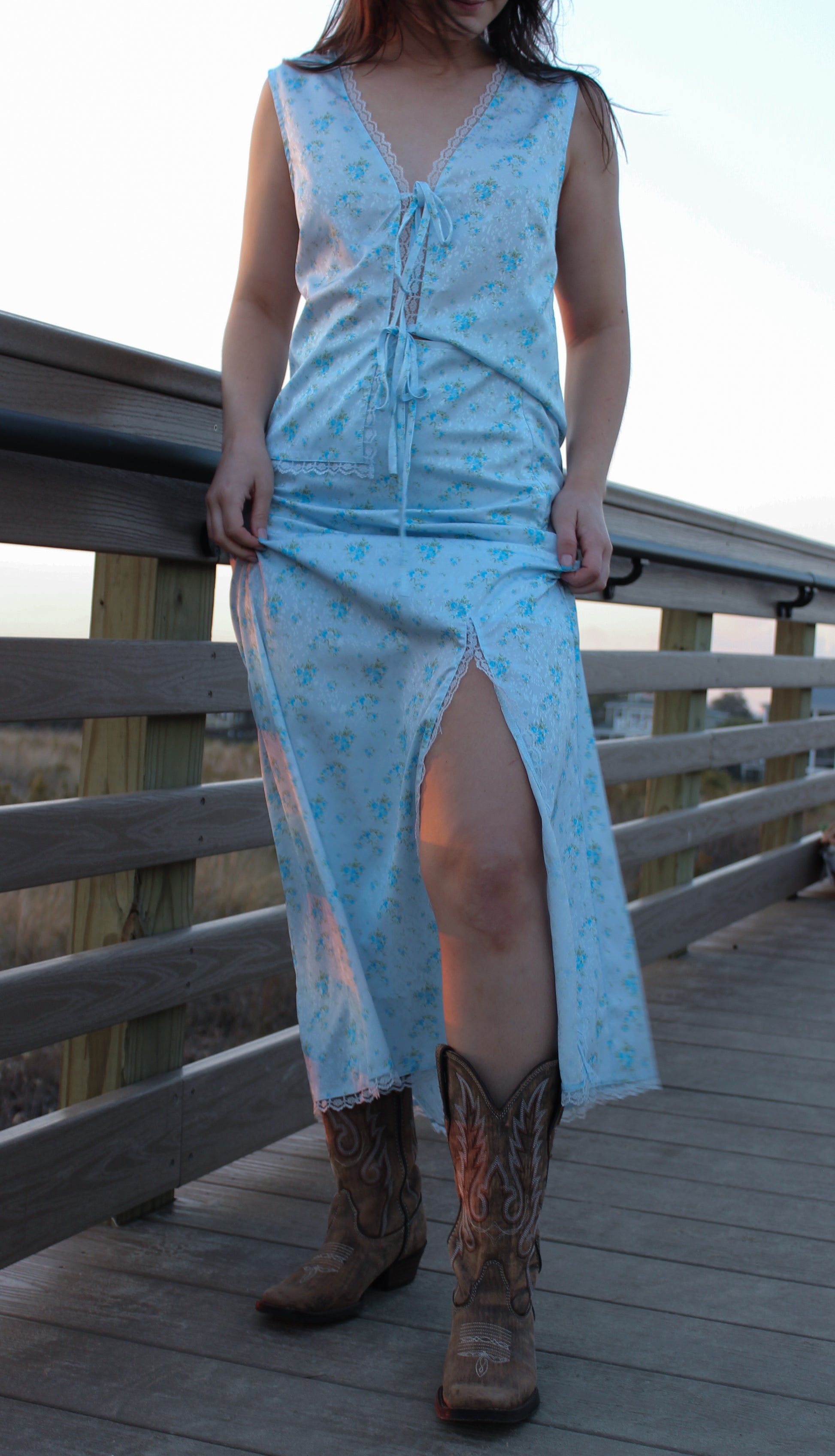 Light blue floral maxi dress with lace details and side slit, paired with brown cowboy boots.