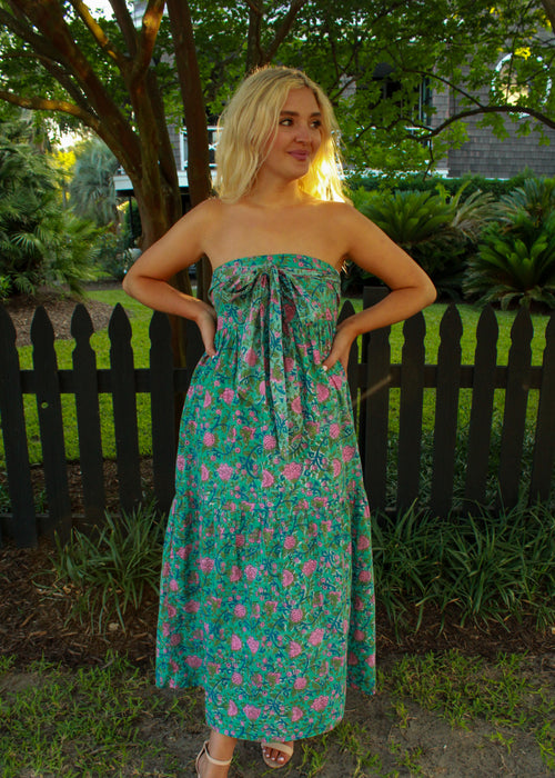 Woman wearing a strapless floral dress standing in a garden.