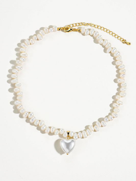 Elegant pearl necklace with gold clasp and a heart-shaped pendant, perfect for stylish occasions.