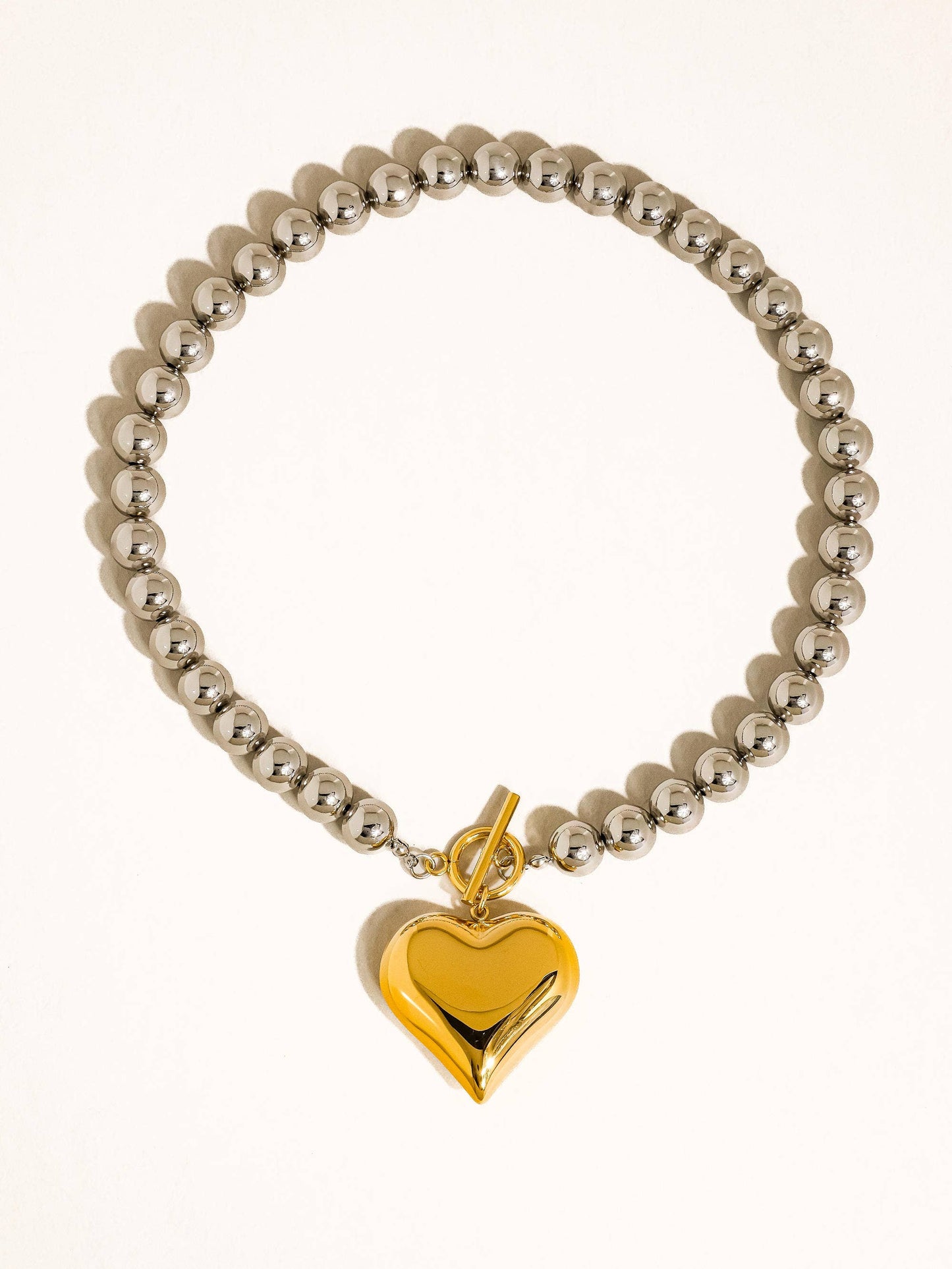 Silver bead bracelet featuring a glossy gold heart charm, perfect for stylish accessories.