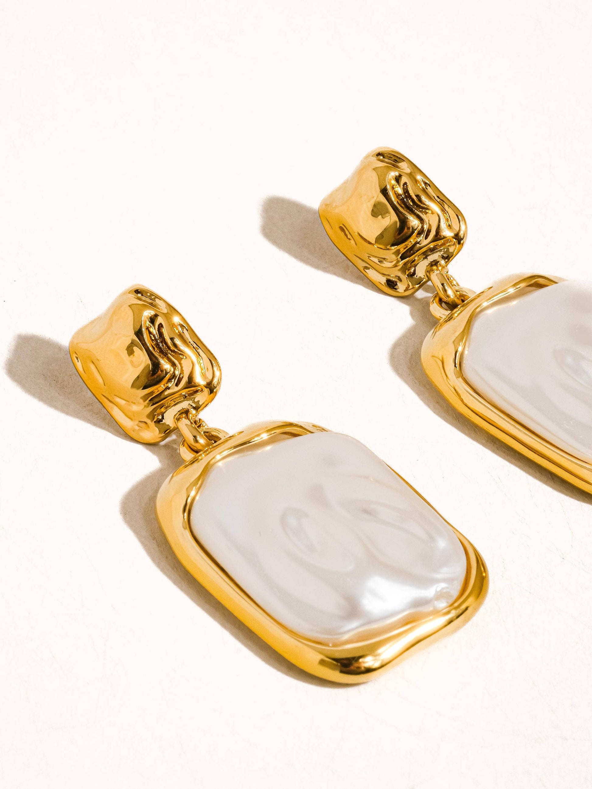 Gold statement earrings with a glossy white resin drop, perfect for adding elegance to any outfit.