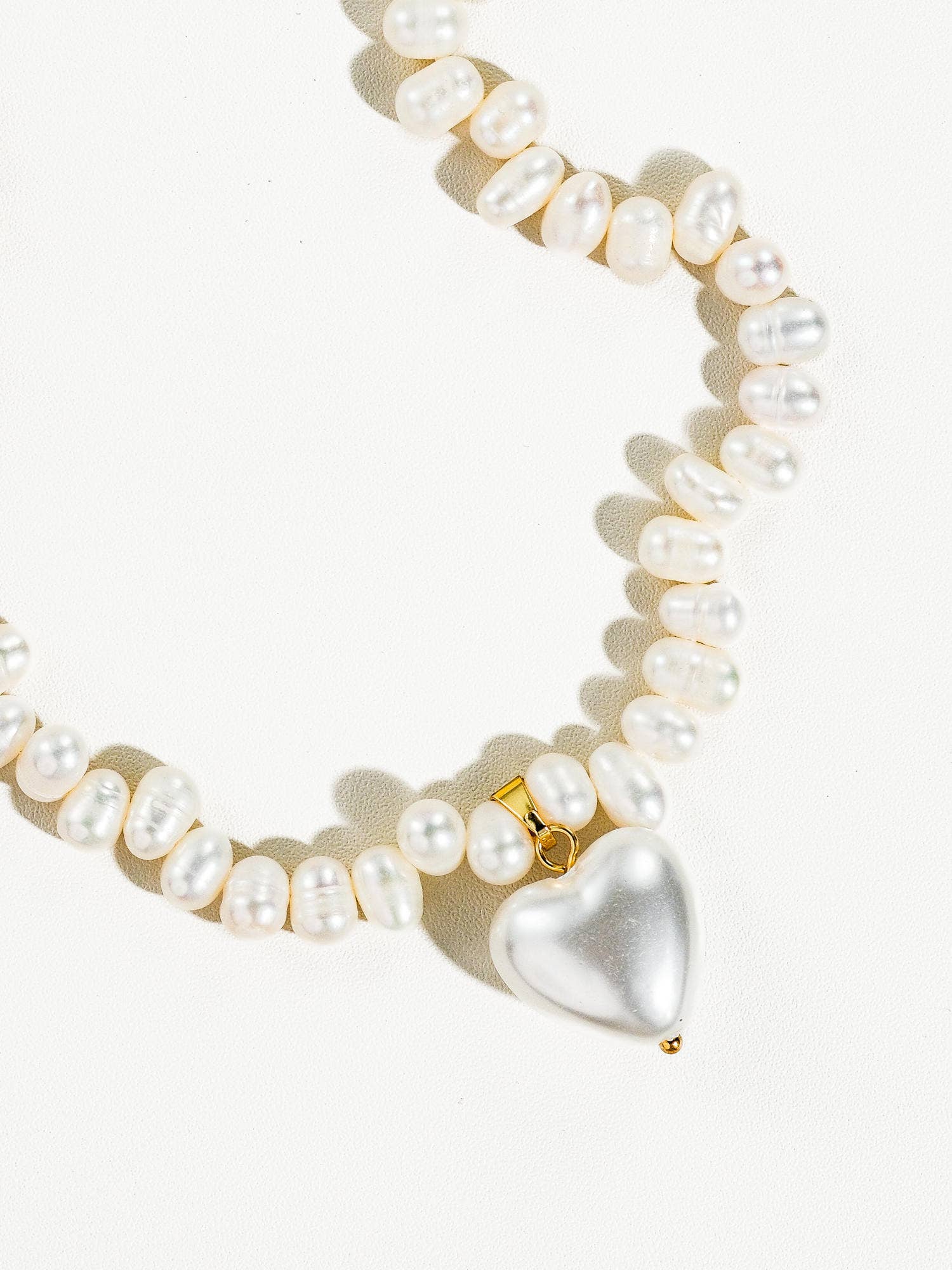 Elegant pearl necklace featuring a heart pendant, crafted from freshwater pearls with gold accents.
